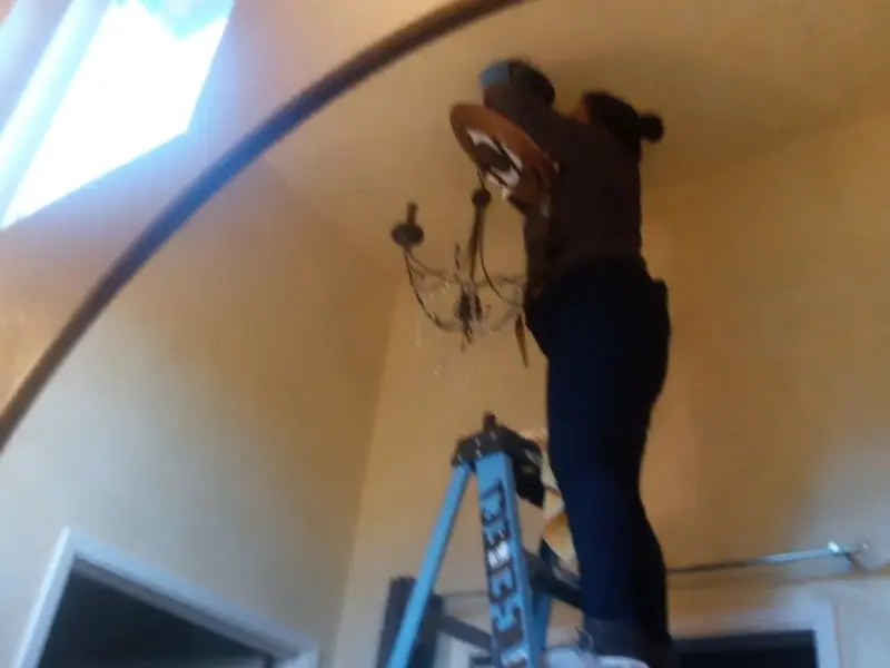 Electrician installing a chandelier in a Friendly residence